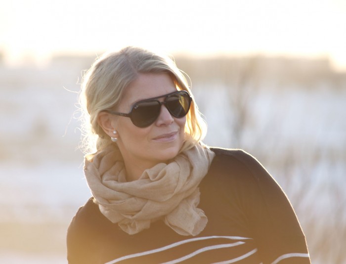 Sunrays in a winter backdrop, blogger Annika Soulcityguide in black Rayban sunglasses and a cashmere scarf