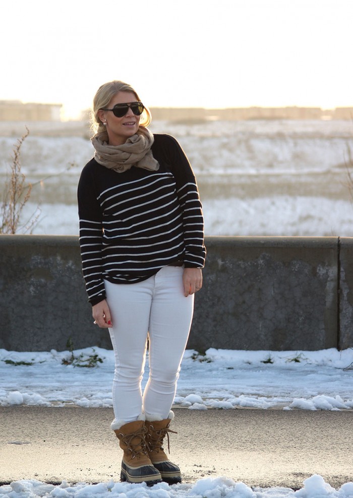 Vinterlandskap i bakgrunden, outfit: vita jeans, sorelboots och randig tröja